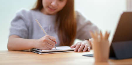 Young businesswoman writing her idea on notebook in comfortable room with office suppliesの写真素材