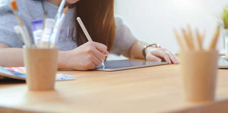 Cropped view of adorable young female freelancer writing her idea concept on tablet for her new projectの写真素材