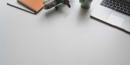 Modern workplace with laptop and office supplies on white desk background, top view with copy spaceの写真素材