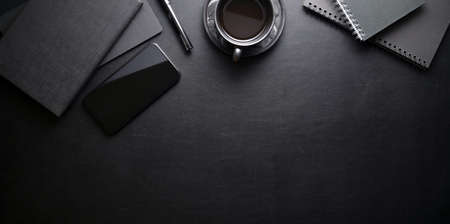 Dark trendy workplace with smartphone and office supplies on black leather table background, top view with copy spaceの写真素材