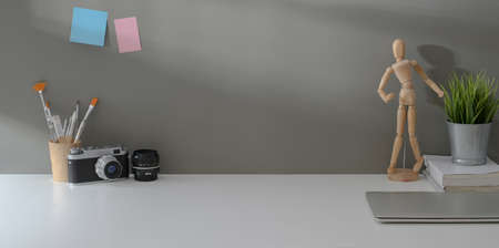Minimal workplace with vintage camera, office supplies and copy space on white table and grey wall backgroundの写真素材