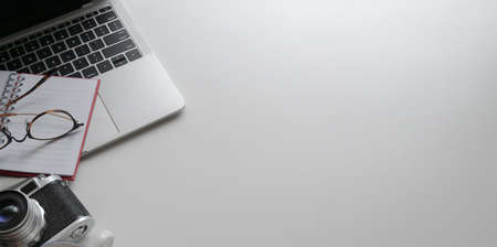 Top view of minimal photographer workplace with laptop and office supplies on white table with copy spaceの写真素材