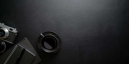 Dark stylish workplace with coffee cup and office supplies on black leather table background, top view with copy spaceの写真素材