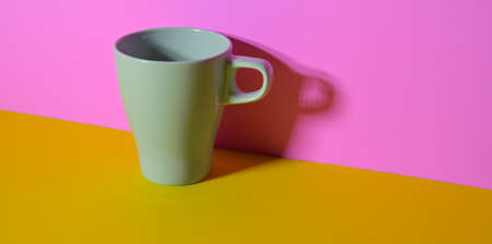 Olive green coffee cup in colourful workplace on yellow desk and pink wall backgroundの写真素材