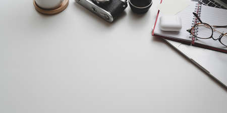 Top view of photographer workplace with laptop, cameras and office supplies on white table background with copy spaceの写真素材