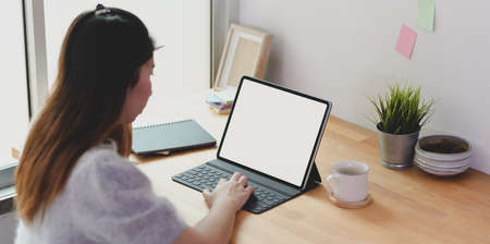 Young female freelancer working on her project with tablet in comfortable workplace with decorationsの写真素材
