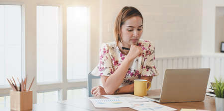 Successful businesswoman working on her project with laptop computer while drinking a cup of coffeeの写真素材