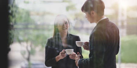 Young professional business partner having coffee break after the meeting outside the office roomの写真素材