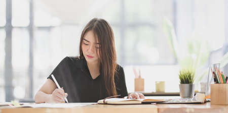 Beautiful young designer editing her concept with tablet in comfortable office roomの写真素材