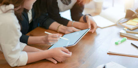 Close-up view of young start up team planing the upcoming project together with tablet in modern office roomの写真素材