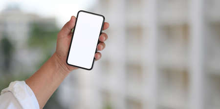 Close-up view of businessman holding blank screen smartphone with blurred building backgroundの写真素材