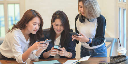 Professional startup team brainstorming the plan together while looking for information on smartphone in modern office roomの写真素材
