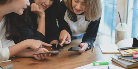 Young startup team brainstorming the strategy together while looking for information on smartphone in modern office room for the upcoming projectの写真素材