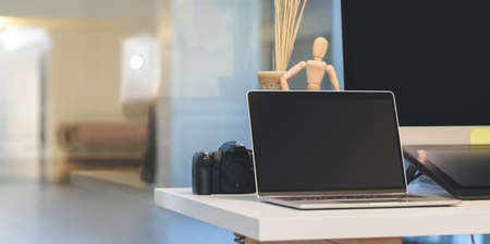 comfortable office with open blank screen laptop computer with mock up frame and office supplies with decorationsの写真素材