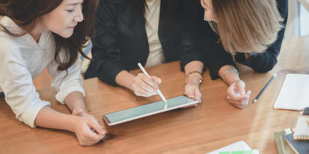 Close-up view of professional startup team planing the project together while using tablet in modern office roomの写真素材