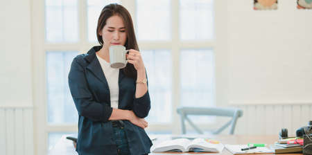 Professional female freelancer having coffee break during the busy time in comfortable workplaceの写真素材