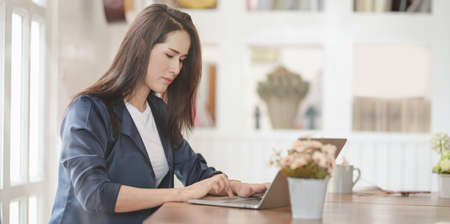 Professional female freelancer working on her project while typing on laptop computer in modern workplaceの写真素材