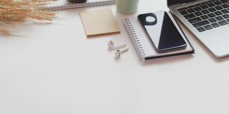 Minimal workplace with open laptop with office supplies and copy space on white table backgroundの写真素材