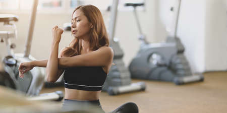 Beautiful Asian female athlete stretching arms after exercise at the modern gymの写真素材