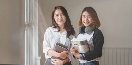 Portrait of two passionate female freelancer smiling and looking at the camera in modern office roomの写真素材