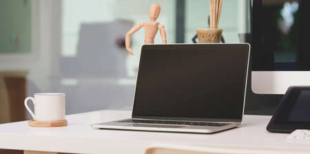 Comfortable office with open blank screen laptop computer with mock up frame and office supplies with decorationsの写真素材