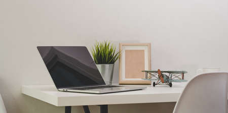 Modern comfortable office with open blank screen laptop computer with mock up frame and office supplies with decorationsの写真素材