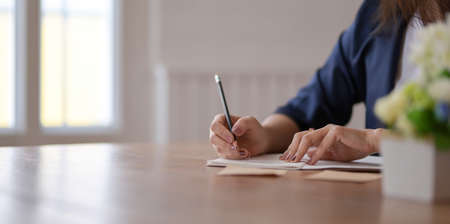 Cropped view of professional freelancer writing her idea concepts on notebook in comfortable workplaceの写真素材