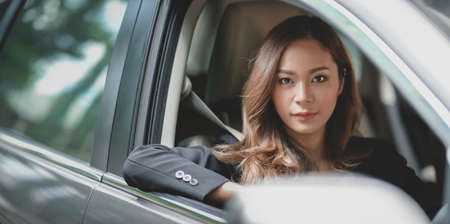 Professional asian businesswoman looking at the camera while driving the car to the officeの写真素材