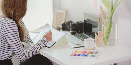 Professional designer editing her project with tablet in modern workplace with office suppliesの写真素材