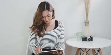Beautiful female designer working on her project with tablet in modern workplaceの写真素材