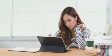 Female designer working on her project with tablet in modern workplace with office suppliesの写真素材
