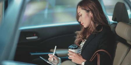 Beautiful professional businesswoman working on the car while heading to the officeの写真素材