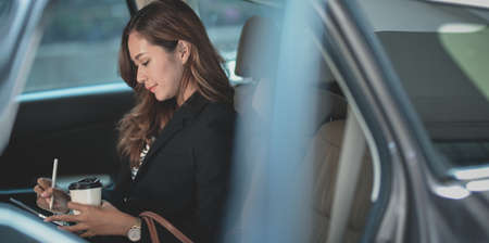 Young professional businesswoman working on the car while heading to the modern officeの写真素材