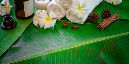 Spa therapy concept, Top view of black stones and towels for massages on green banana leaves backgroundの写真素材
