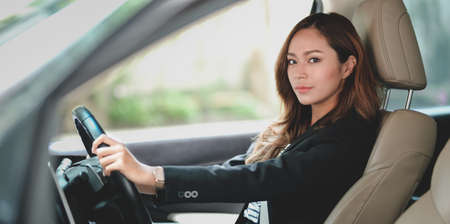 Professional asian businesswoman looking at the camera while driving the car to the officeの写真素材