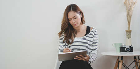 Professional female designer working on her project with tablet in modern workplace with office suppliesの写真素材