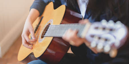 Cropped view of woman playing acoustic guitar in comfortable roomの写真素材