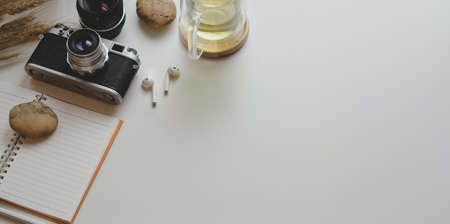 Top view of minimal workplace with vintage camera and office supplies with decorations on white table backgroundの写真素材