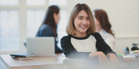 Portrait of young freelancer smiling at the camera while working with team member in the office
