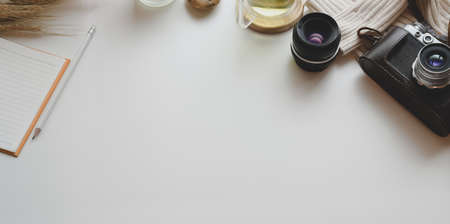 Top view of minimal workplace with vintage camera and office supplies with decorations on white...