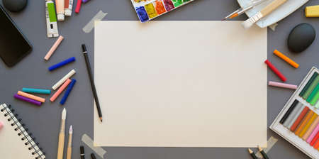 Top view of professional artist workplace with soft pastel colours and painting tools on grey desk backgroundの写真素材