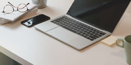Minimal workplace with open laptop and smartphone with copy space on white tableの写真素材