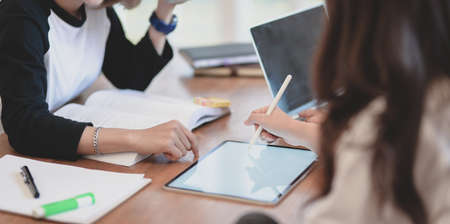 Close-up view of young professional business team discussing the plan about the upcoming project together and writing on tabletの写真素材