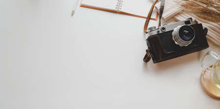 Modern photographer workplace with camera, office supplies and copy space on white deskの写真素材