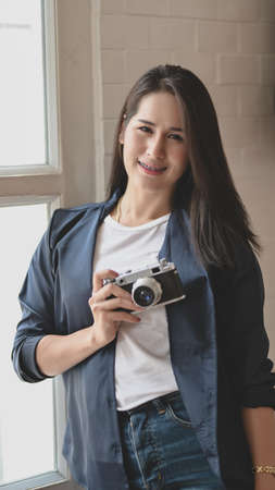 Portrait of beautiful professional photographer holding camera and smiling to the cameraの写真素材