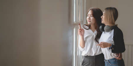 Young female freelancer talking together while looking out of the window