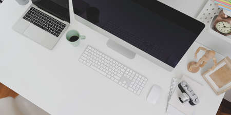 Top view of trendy workplace with desktop computer and office supplies with copy space on white tableの写真素材