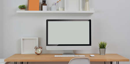 Minimal workplace with desktop computer and office supplies with decorations on wooden tableの写真素材