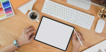 Top view of professional designer editing his work on tablet on wooden table with decorations and copy spaceの写真素材