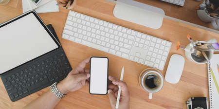 Top view of professional designer looking for idea on smartphone on wooden table with decorations and copy spaceの写真素材